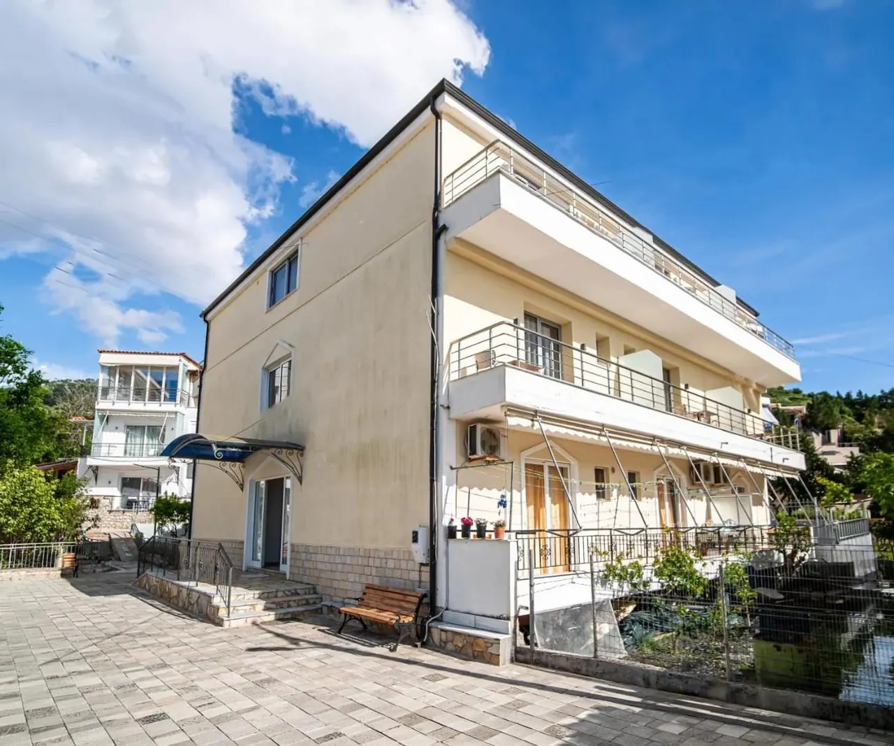 The cream façade of Vourtaréa Guesthouse with its navy entrance awning and stone base