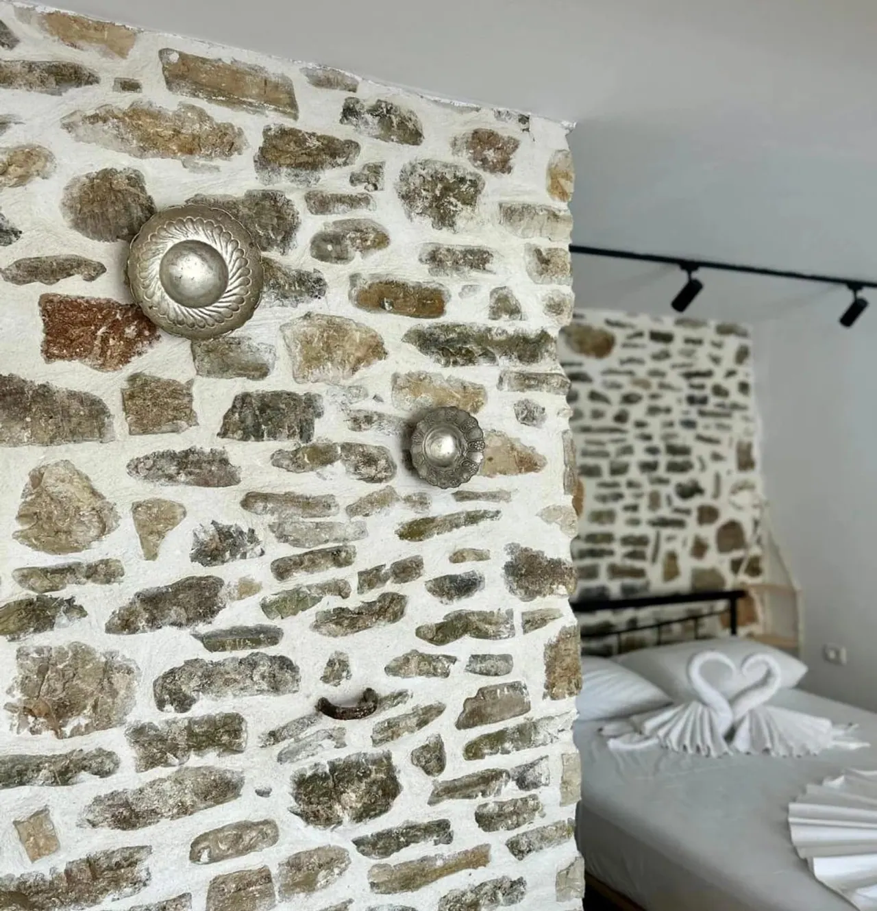 Silver bosses set into the original stone wall of the old house, with a bed beyond