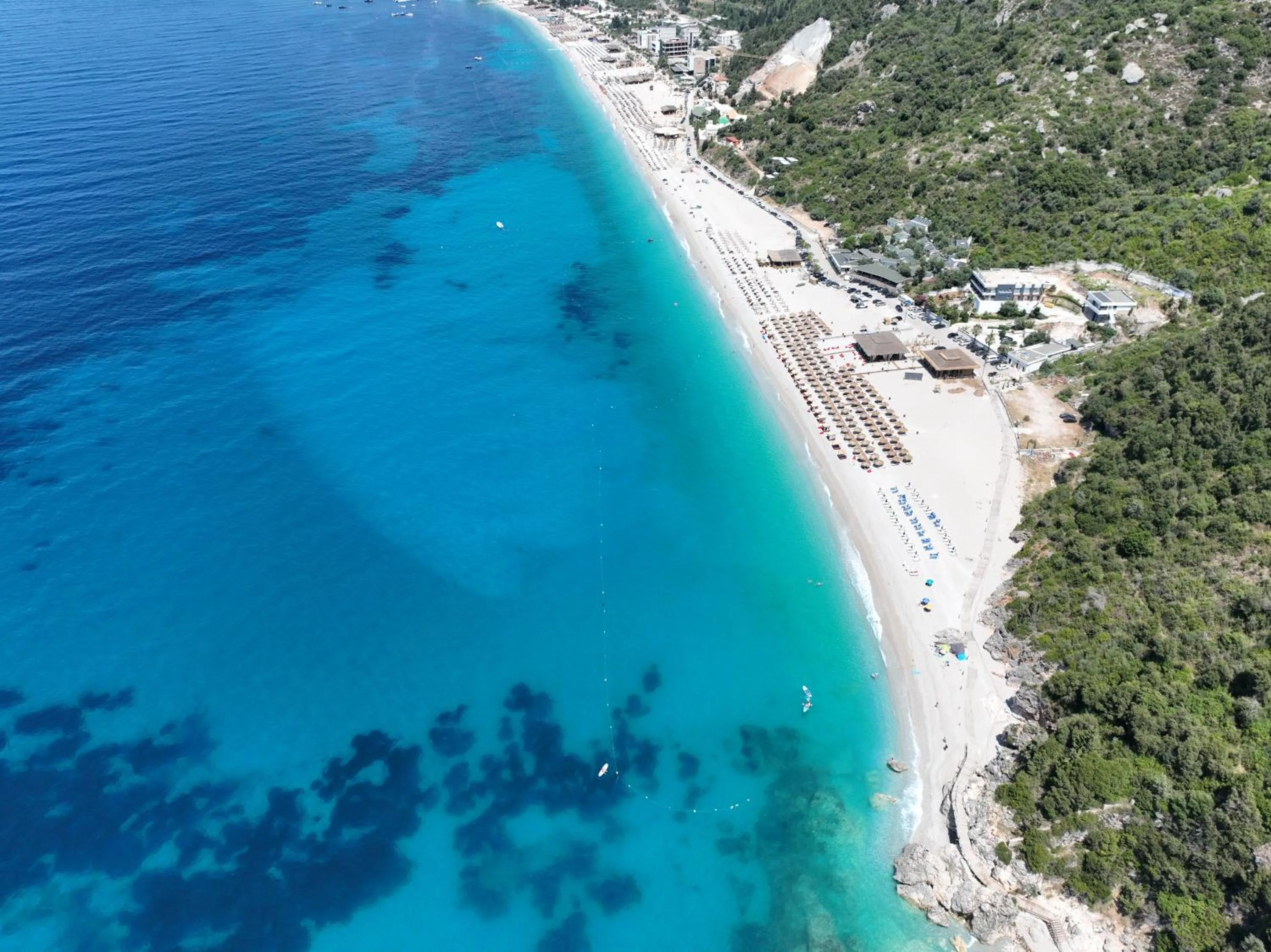 The southern end of Dhërmi Beach from the air, where Alevra stands among the trees