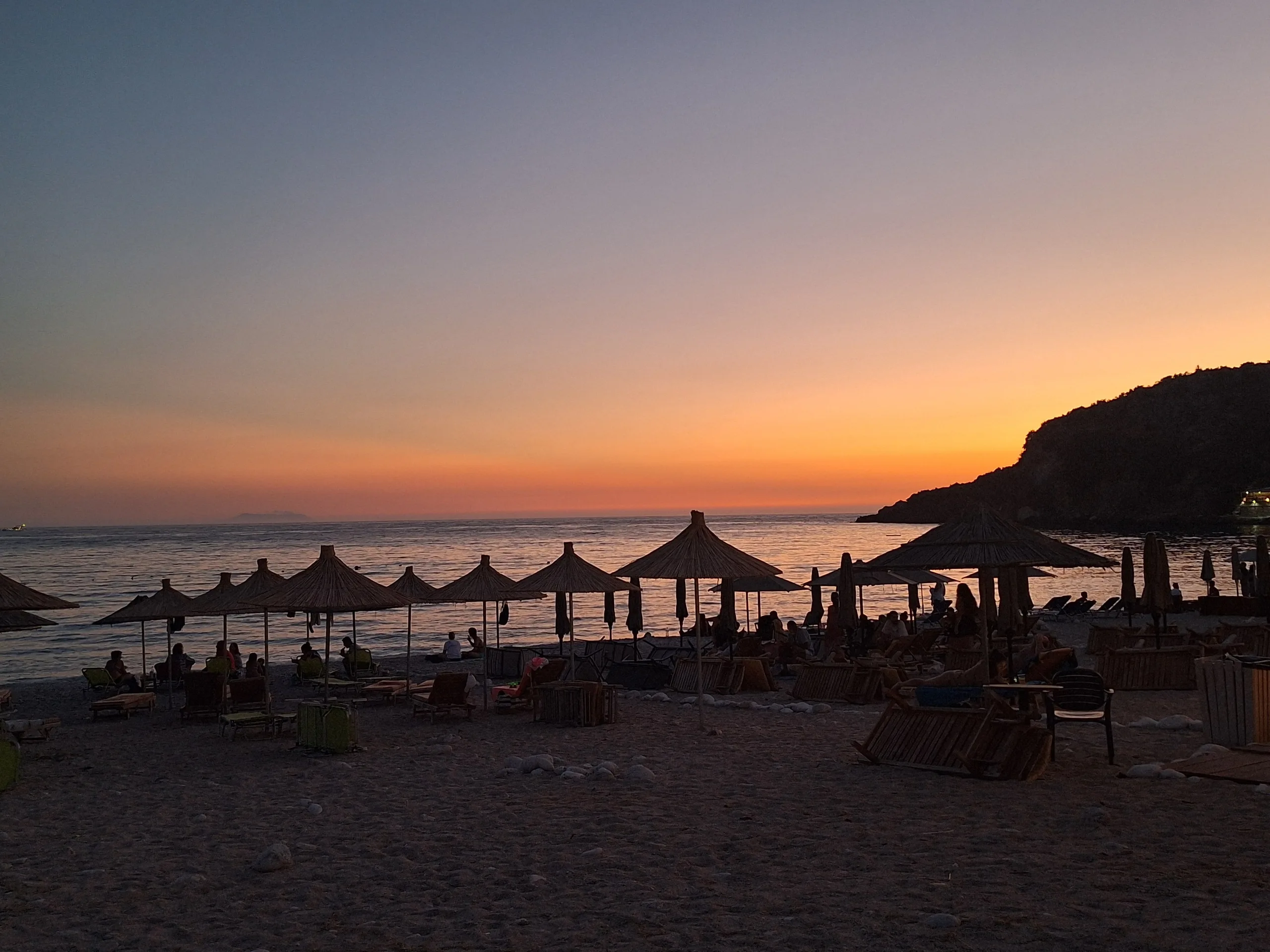Livadh Beach at sunset in front of Camping Livadh, straw umbrellas in silhouette
