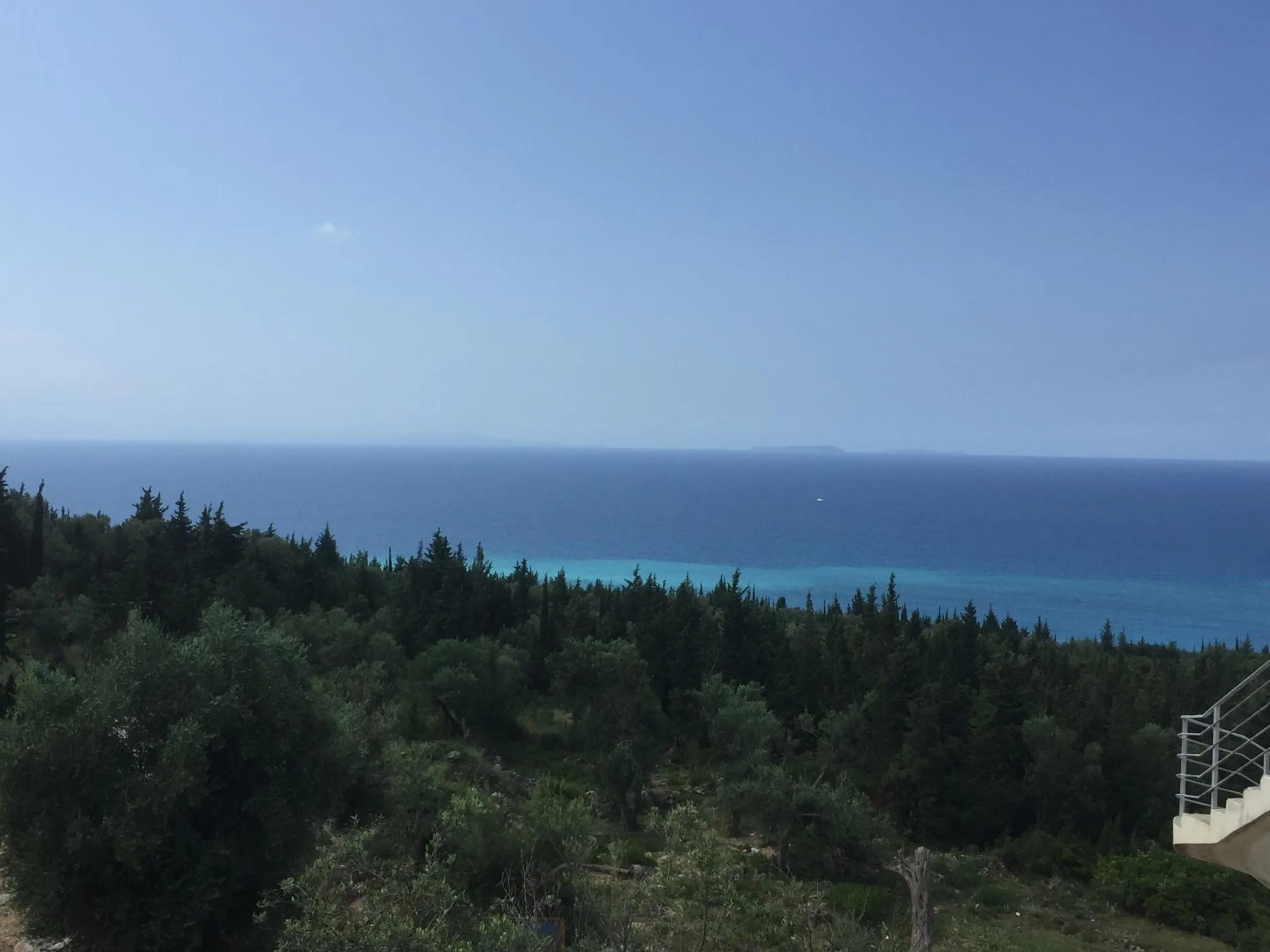 The sea over olive and cypress trees from Drimades Blue Rooms in Drymades, Dhërmi