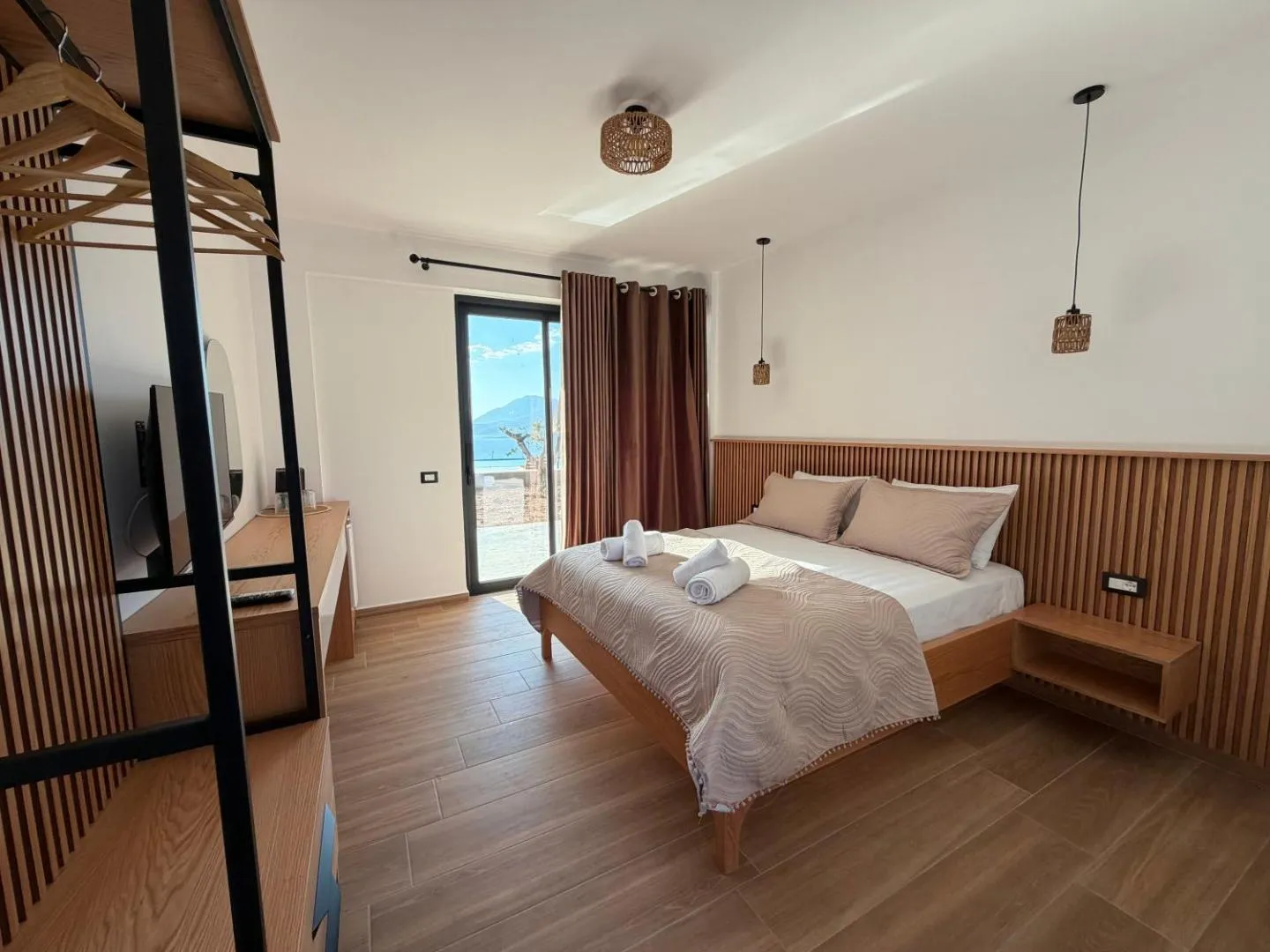 The quadruple room at Filikuri Boutique Hotel, oak slat headboard and a full-height window onto the hillside