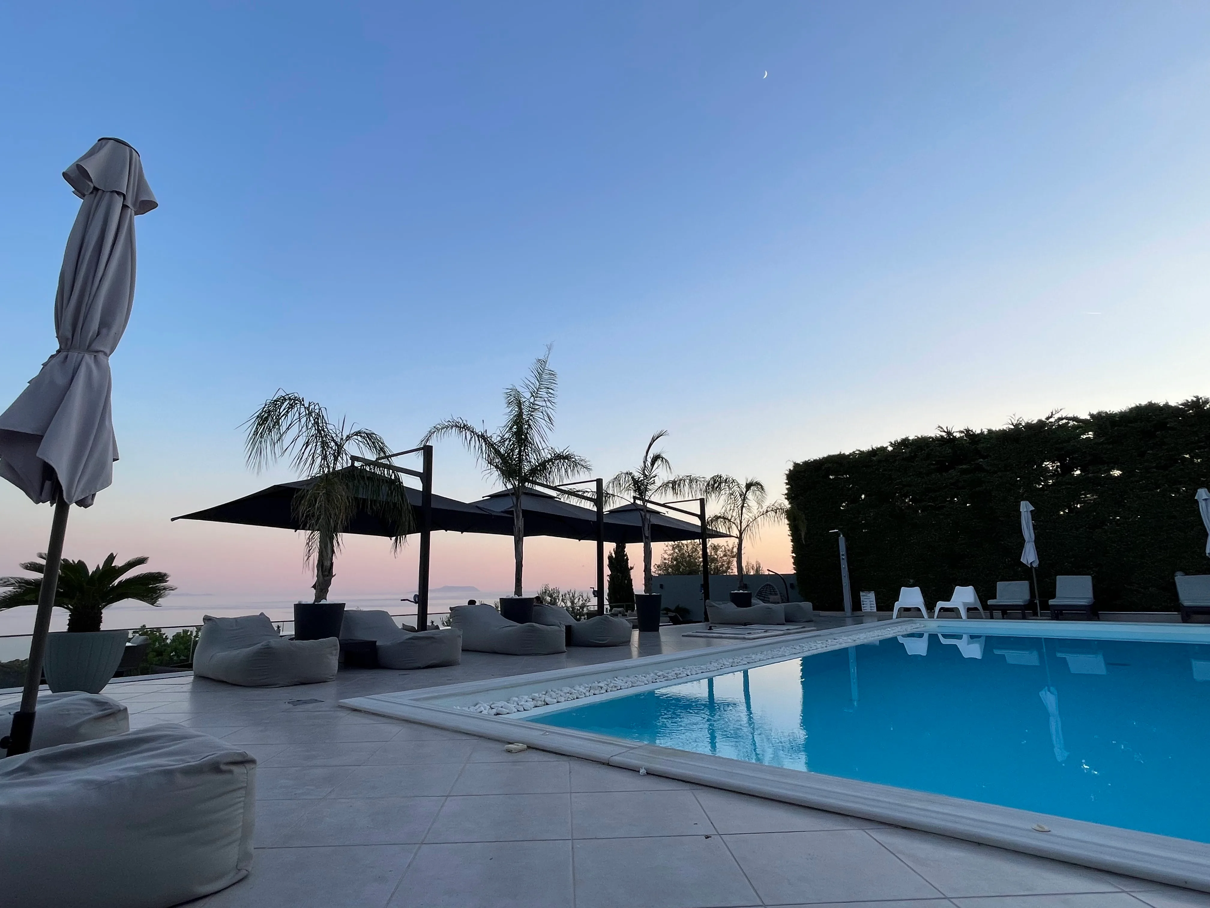 The pool terrace at Golden View Residence at dusk, the sea and an island on the horizon above Dhërmi