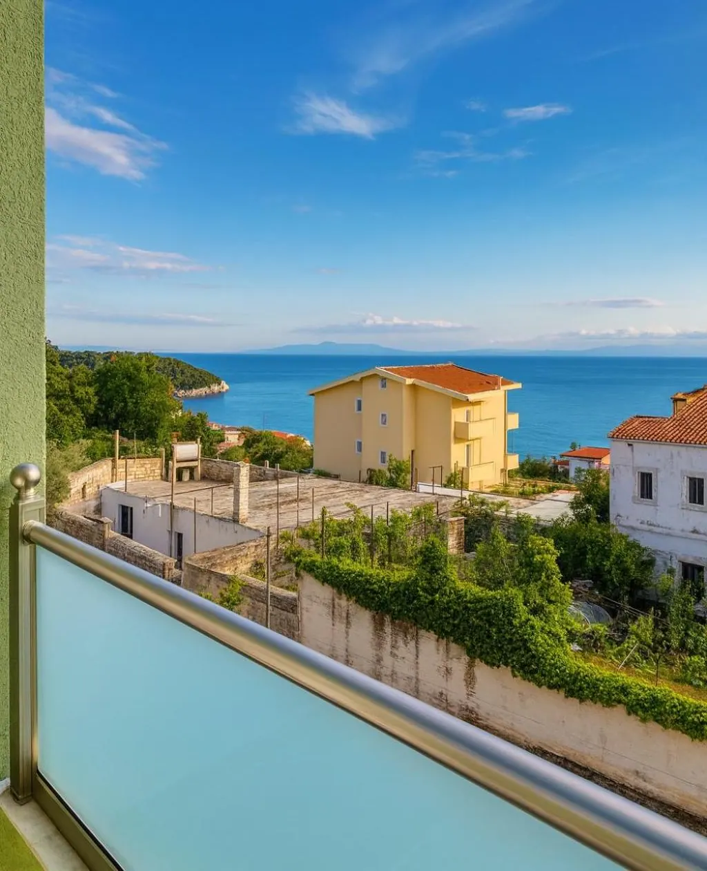 The view from a balcony at Oscar's Apartments in Drymades over olive gardens and village roofs to the sea